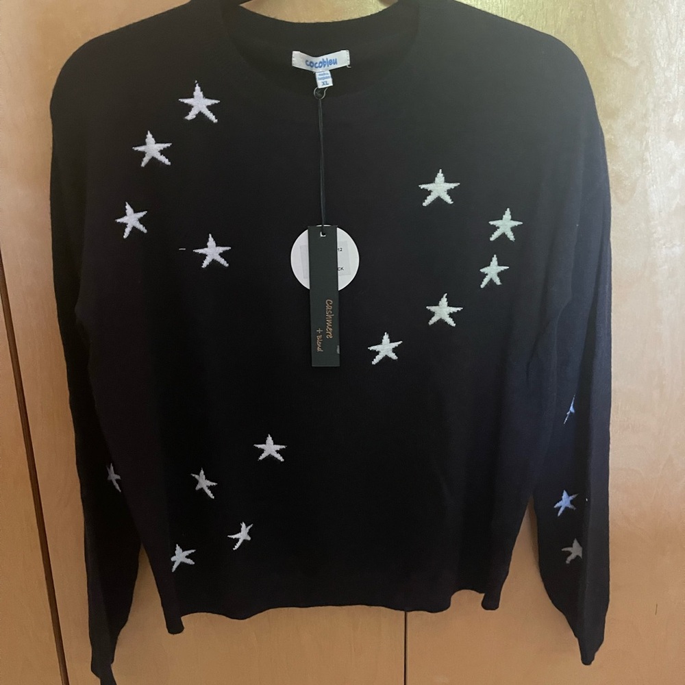 Black sweater w/ white stars. Soft with nice stretch.  Viscose/nylon/cashmere.
